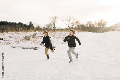 Cheerful children running in the snowy field