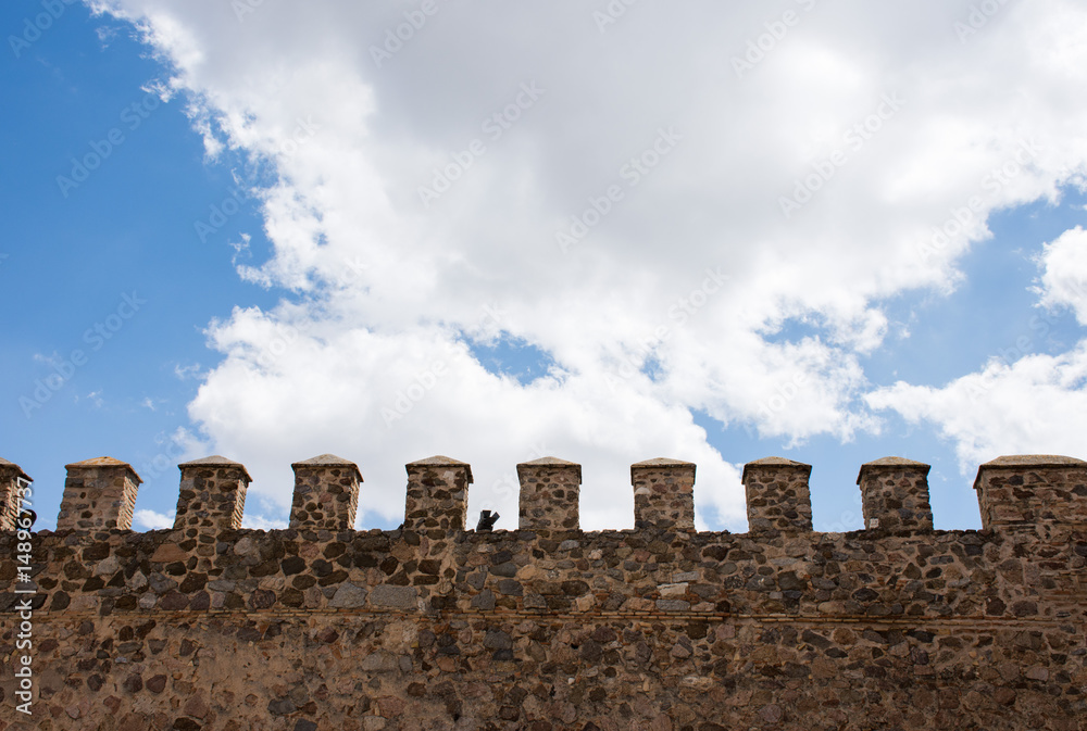 Castle wall and white clouds against the blue sky. Toledo, Spain