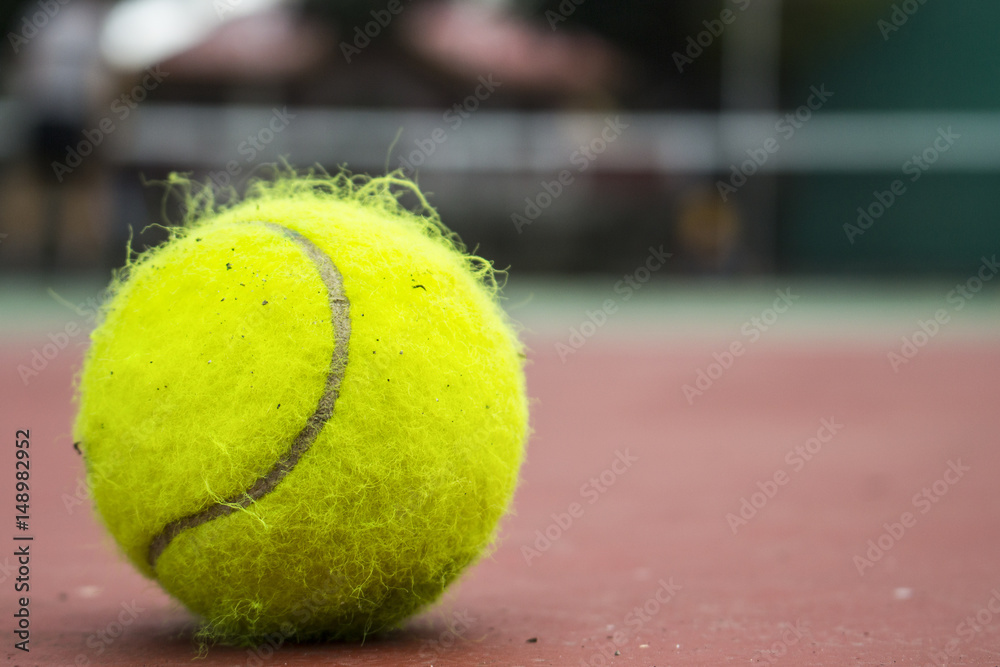 Yellow tennis ball on red court. Fluffy felt tennis ball closeup photo.
