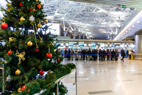 Christmas tree in the airport and people at the check-in counters