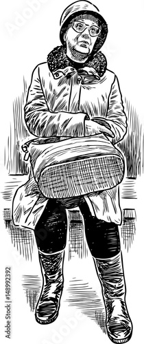 An elderly woman sits on a park bench