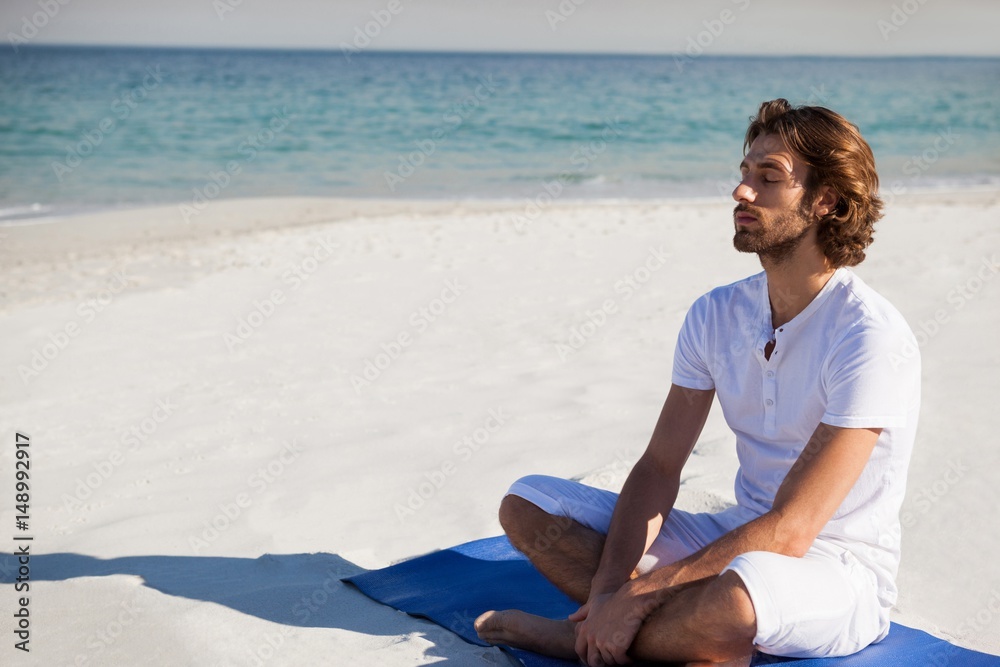 Man with eyes closed meditating at beach