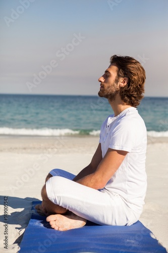 Man performing yoga at beach