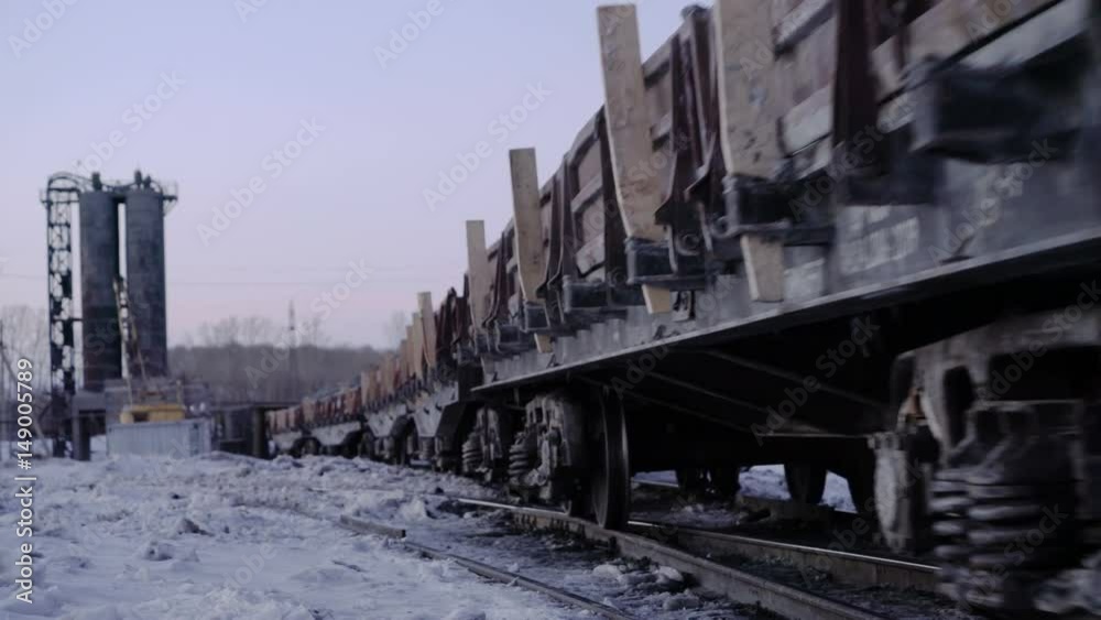 Outlook shot of freight train with empty gondola cars moving along a single-track railway in winter. Outlook shot of freight train with empty gondola cars moving along a single-track railway in winter.