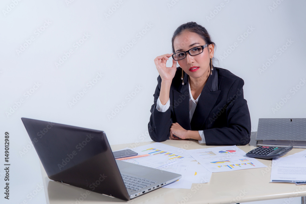 Businesswoman sitting at desk in office. He looks at the camera and smiling. Businesswoman sitting at desk in office. He looks at the camera and smiling.