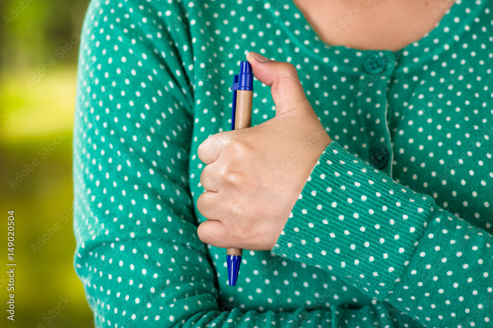 Fototapeta premium Close-up of a female hand holding a pen. fiddling concept