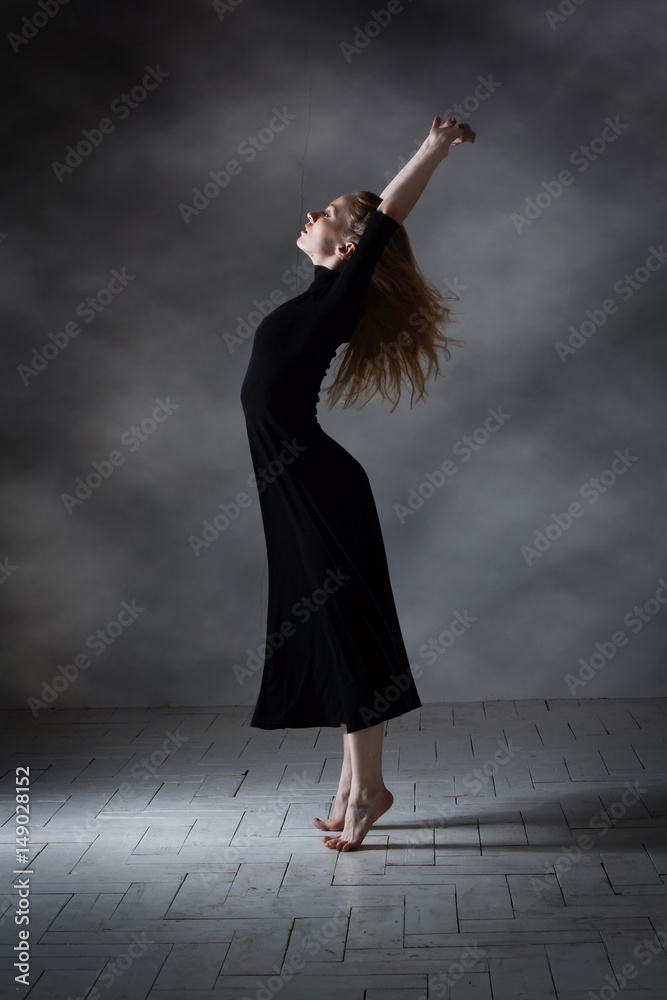 Modern ballet dancer posing on dark background Modern ballet dancer posing on dark background