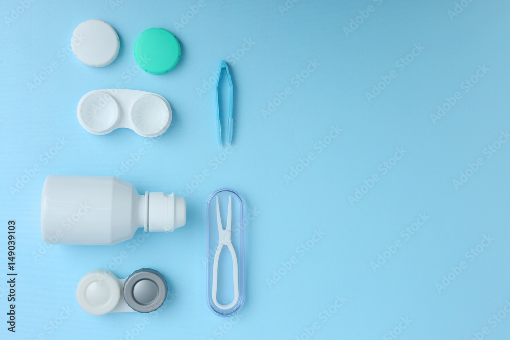 Cases for contact lenses, tweezers and bottle of solution on blue background Cases for contact lenses, tweezers and bottle of solution on blue background