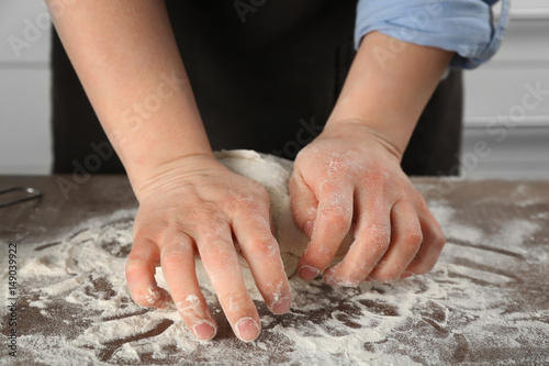 Female chef kneading dough in kitchen