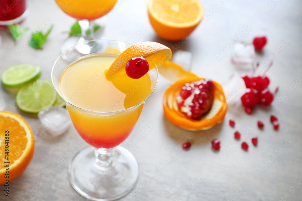 Glass of Tequila Sunrise cocktail with ingredients on grey background Glass of Tequila Sunrise cocktail with ingredients on grey background