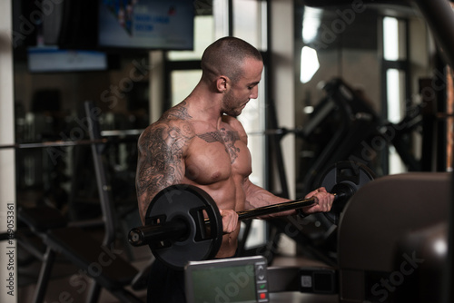 Man In The Gym Exercising Biceps With Barbell
