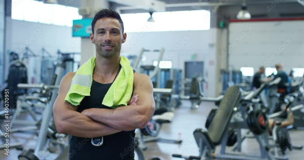 Portrait of a handsome guy in the gym, in good shape and body, smiling at the camera, background of the simulators, barbells. Concept: to love sports, go to the gym, eat right, slim body, be healthy Portrait of a handsome guy in the gym, in good shape and body, smiling at the camera, background of the simulators, barbells. Concept: to love sports, go to the gym, eat right, slim body, be healthy
