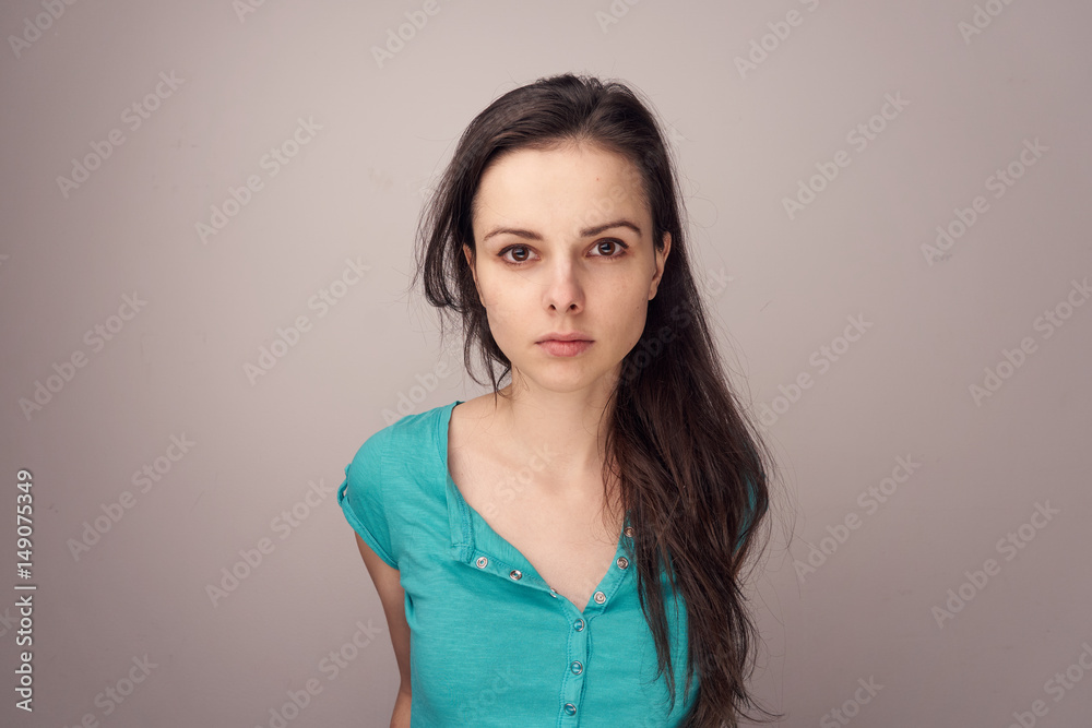 brunette in a blue shirt on a gray background brunette in a blue shirt on a gray background