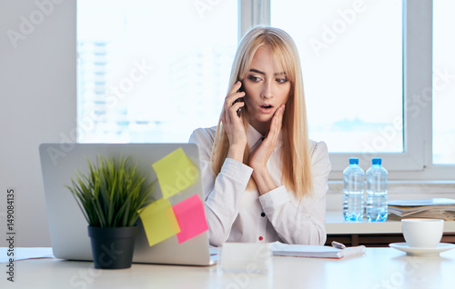 upset, surprised business woman talking on the phone at the office