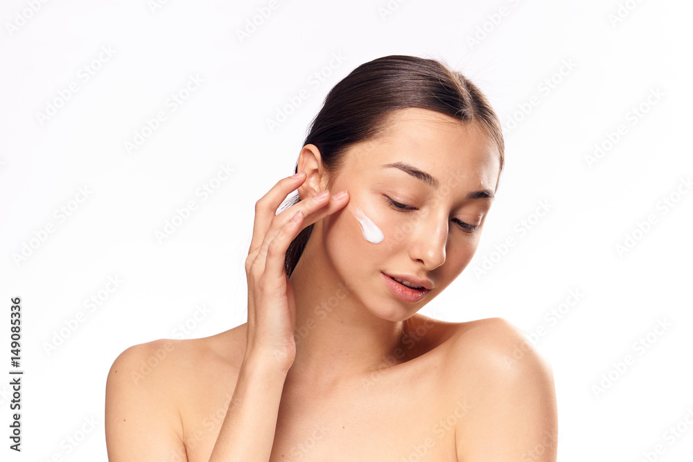 a woman puts a light cream on the skin of the face