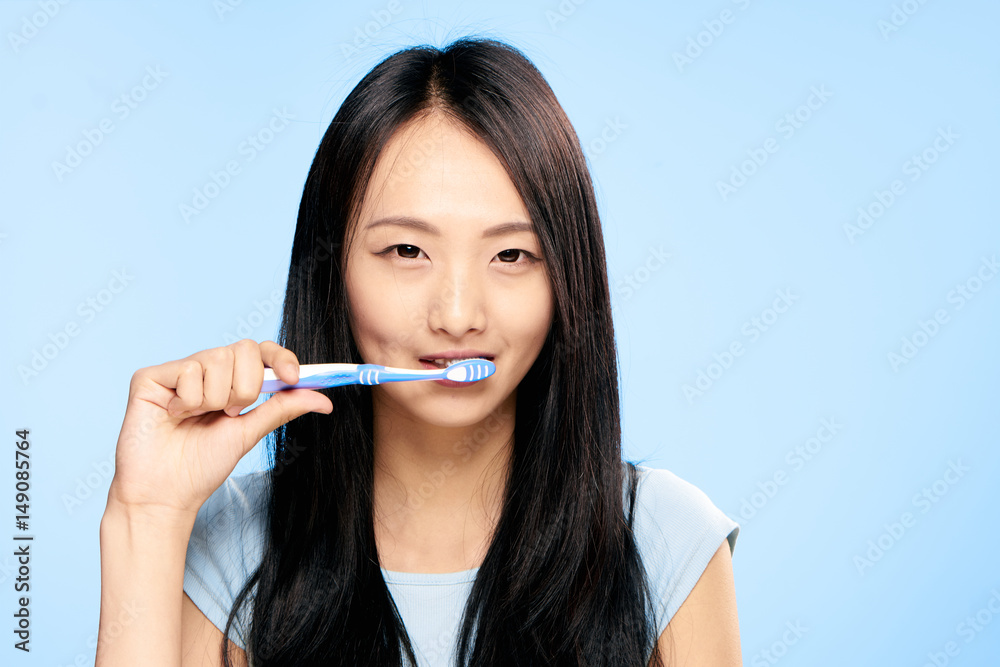happy brunette brushes teeth, blue background happy brunette brushes teeth, blue background