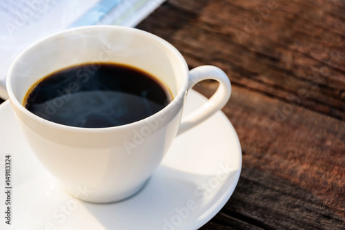 coffee cup clock and news paper on old wooden table