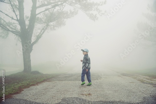 Little boy walking through the fog in forest : Soft focus