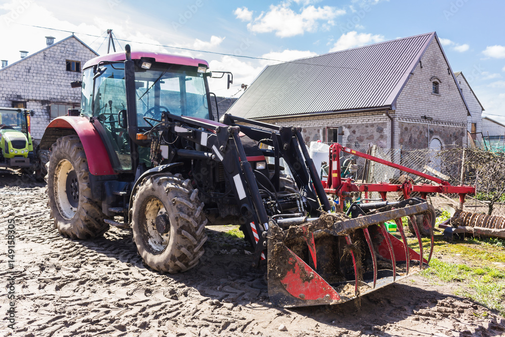 Agricultural machinery and equipment . Tractor with front loader for manure. The yard of a dairy farm. Podlaskie, Poland. Agricultural machinery and equipment . Tractor with front loader for manure. The yard of a dairy farm. Podlaskie, Poland.
