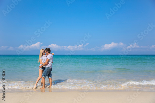 Young happy couple on beach smiling holding around each other. Love story