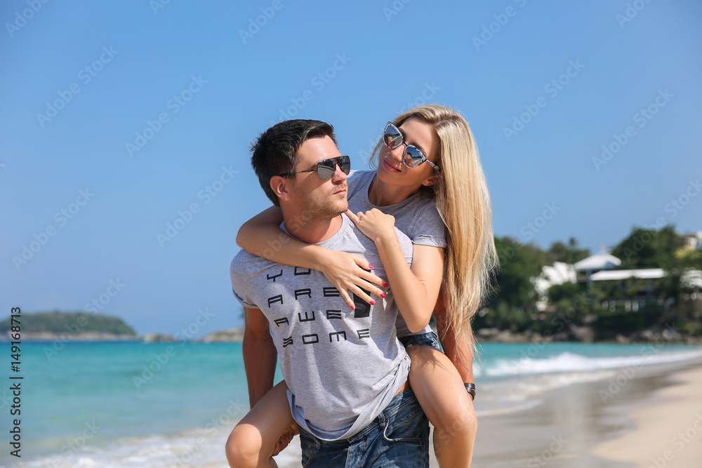 Young beautiful happy couple having fun on the beach. Piggyback rides. Positive human emotions, feelings. Love story