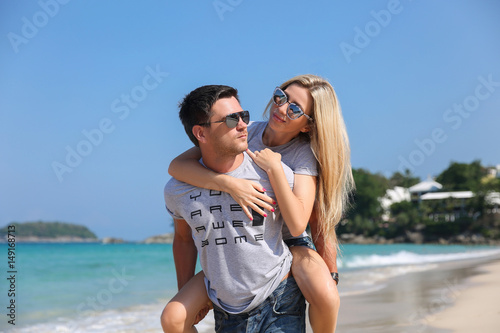 Young beautiful happy couple having fun on the beach. Piggyback rides. Positive human emotions, feelings. Love story © Ilya