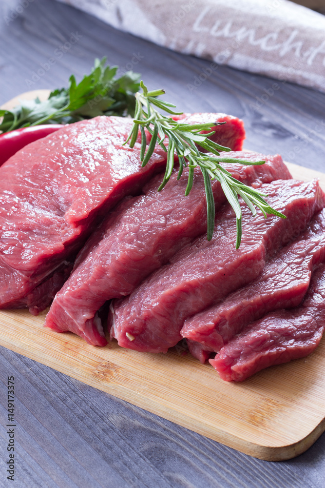 Fresh raw beef steak with rosemary on a wooden table. Dark background. Fresh raw beef steak with rosemary on a wooden table. Dark background.