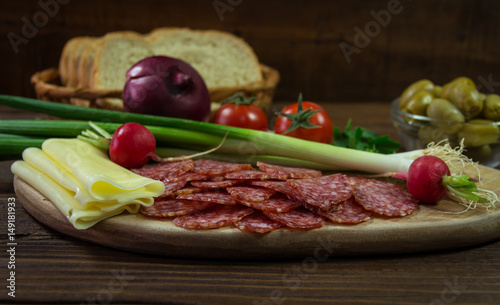 Wooden board with salami, cheese and vegetable