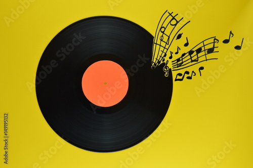 old black vinyl record with blank orange label centered on yellow background with notes and staves coming from it