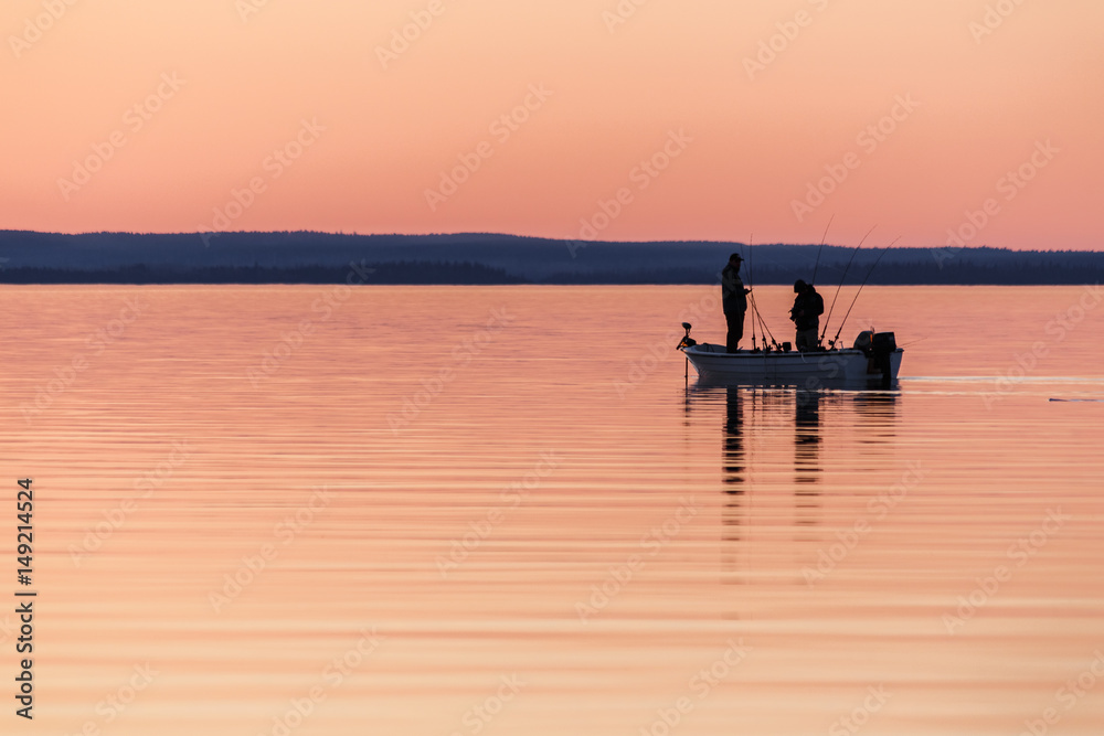 Two people fishing from small boat at sunset