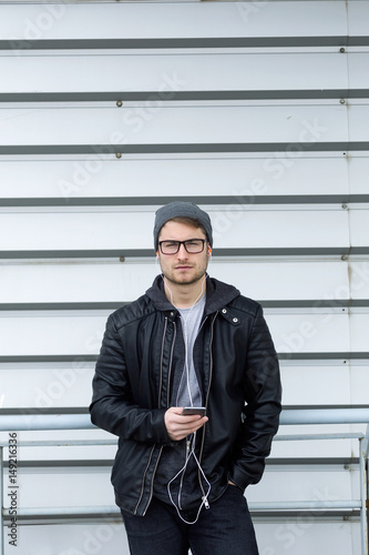 Fotografi Modern young man listening to music with mobile phone in the street