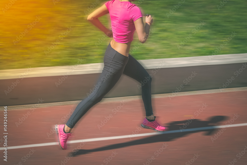 Female jogger running on athletic track. Motion blur. Female jogger running on athletic track. Motion blur.