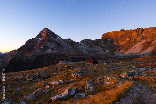 Alpine meadow and pasture set amid high altitude mountain range at sunsets. The Italian Alps, famous travel destination in summertime.