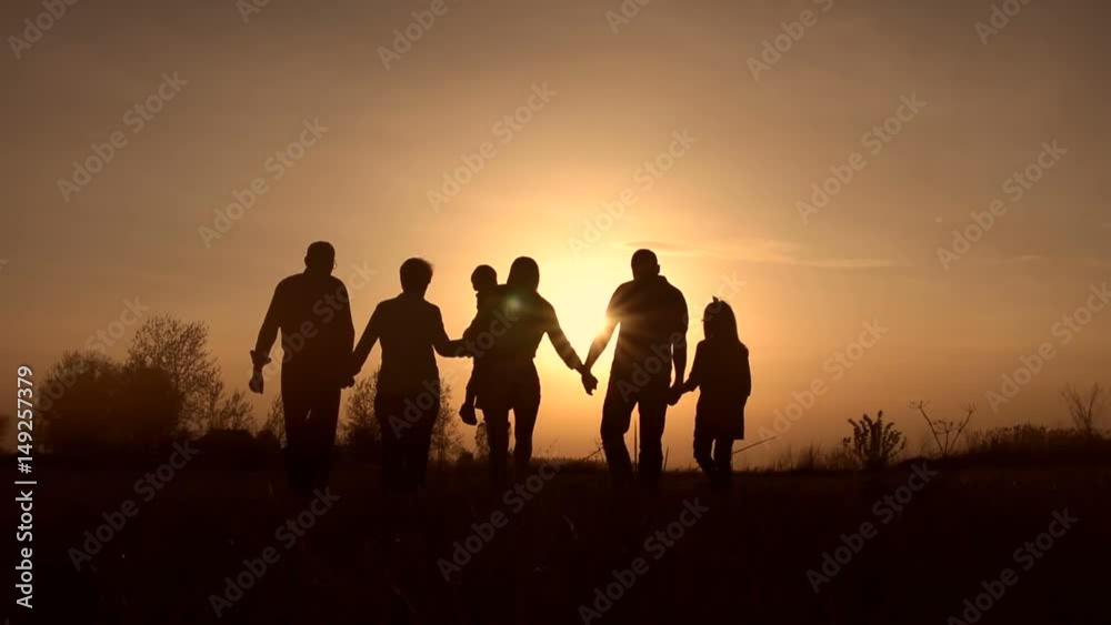 Three generation family walk in meadow at sunset Three generation family walk in meadow at sunset