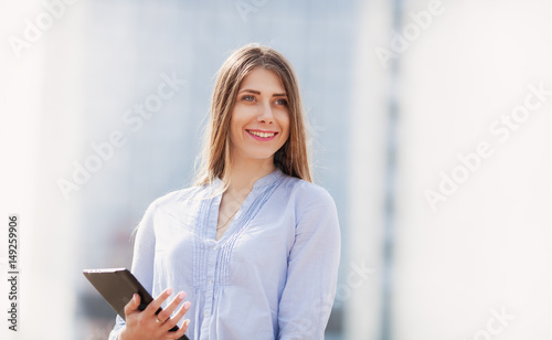 Portrait of pretty businesswoman in smart casual using digital tablet outdoors. copy space