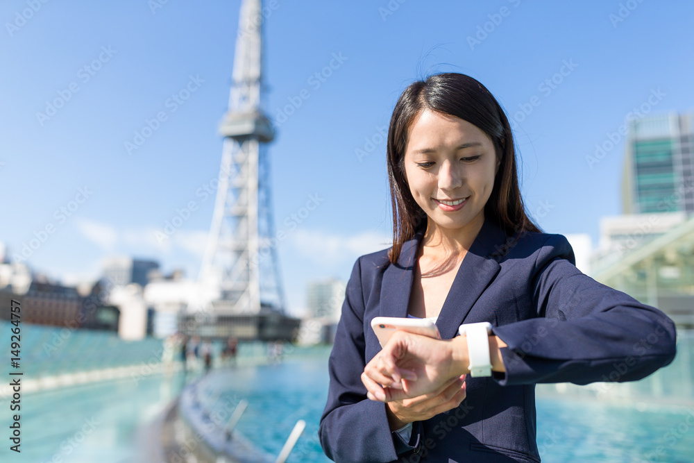 Businesswoman using mobile phone and smart watch