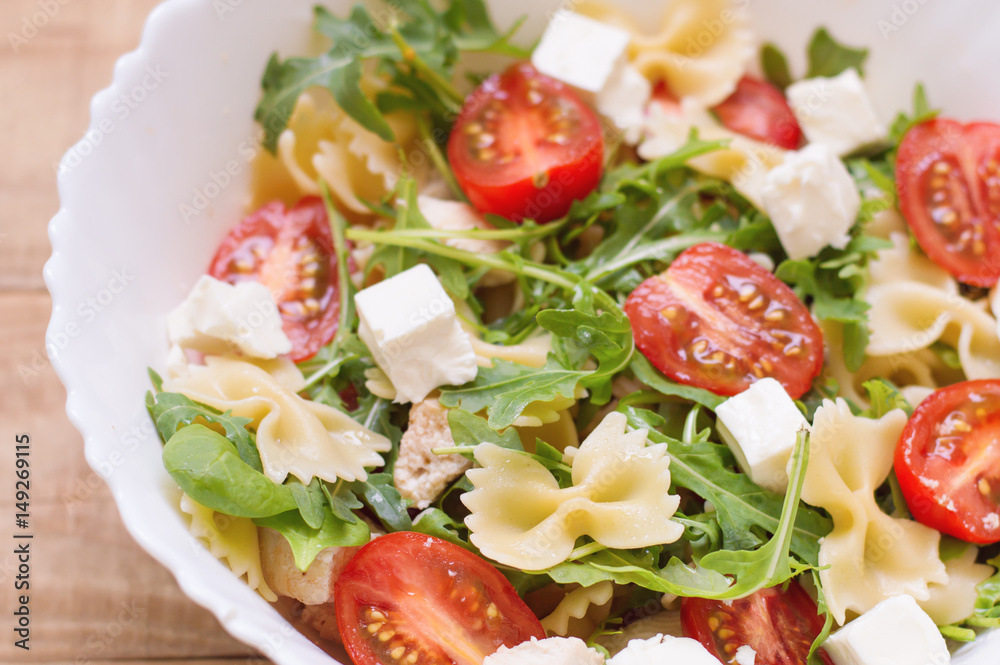 Big portion of homemade pasta salad with red cherry tomatoes, feta cheese, chicken breast, baby spinach leaves, arugula (rocket leaves) and farfalle. Appetizer. Healthy eating Big portion of homemade pasta salad with red cherry tomatoes, feta cheese, chicken breast, baby spinach leaves, arugula (rocket leaves) and farfalle. Appetizer. Healthy eating