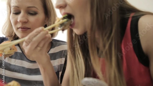 two happy woman eating sushi in restaurant Japanese cuisine, uses chopsticks. close-up rolls on a plate