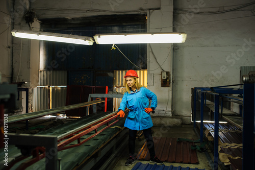 woman in red safety helmet at metal tile roof manufacturing factory