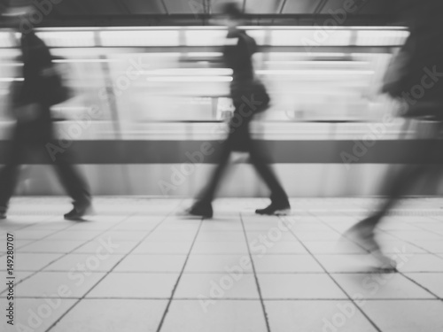 Subway train leaving station. People coming to or leaving the platform. Motion blur. City life.Black and white image.