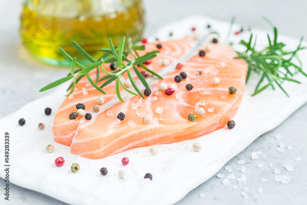 Fresh raw salmon steak with seasonings on white board, horizontal Fresh raw salmon steak with seasonings on white board, horizontal