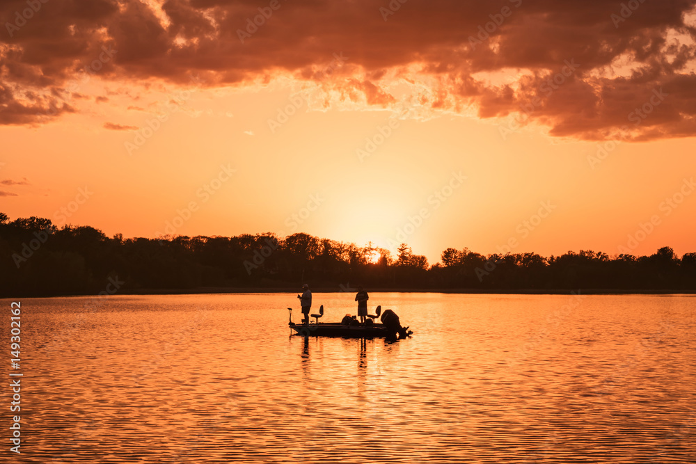 People are boating and fishing under sunset