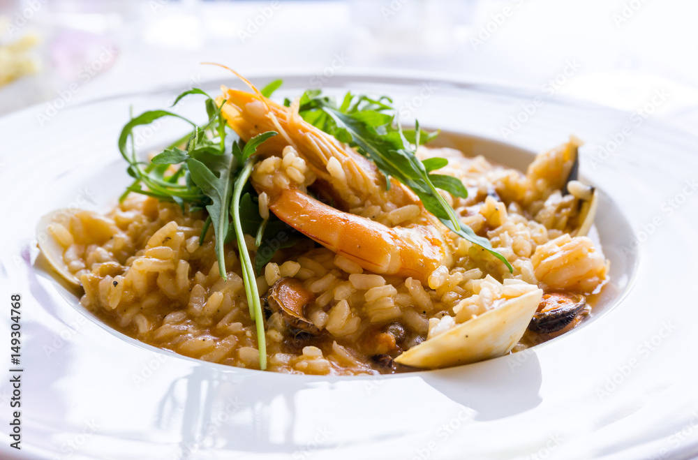 Tasty risotto with Shrimp, fresh herbs vegetables on a white plate Tasty risotto with Shrimp, fresh herbs vegetables on a white plate