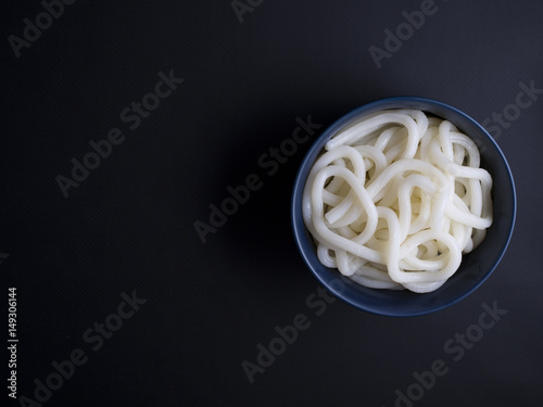 Принти на полотні Cooked, thick udon noodles from Korea in small blue bowl, isolated on black back