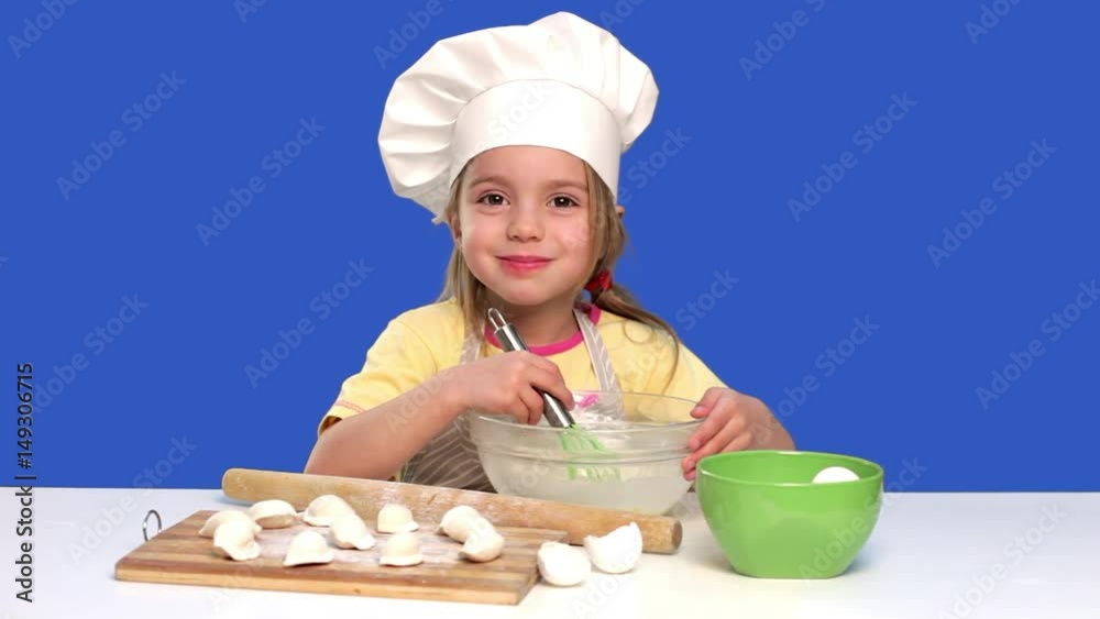 little girl chef prepares food in a studio on blue, concept cooking little girl chef prepares food in a studio on blue, concept cooking
