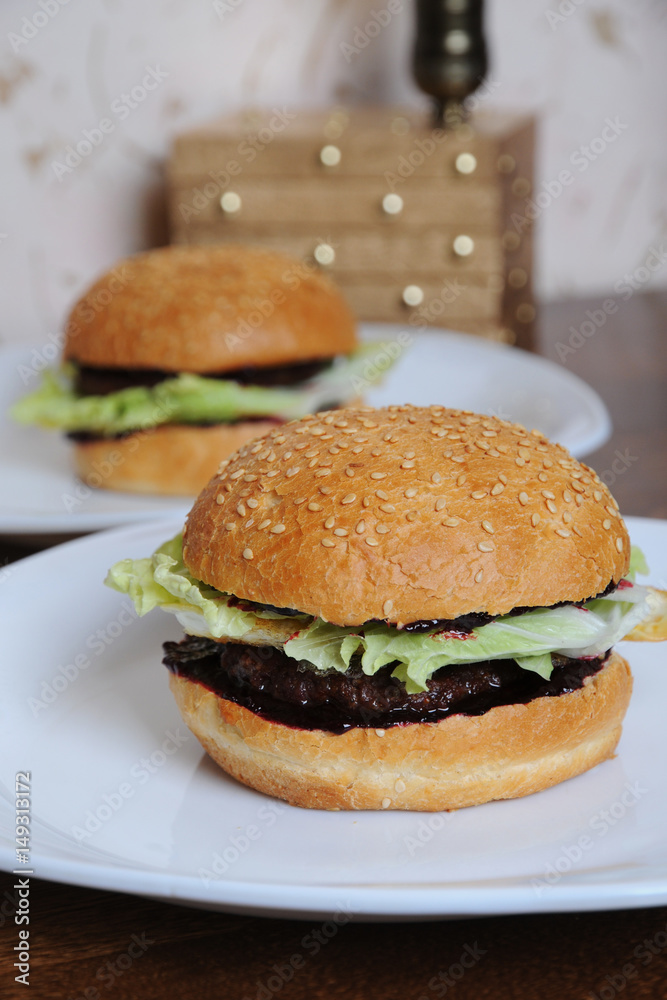 Two burgers with berry sauce on white plates Two burgers with berry sauce on white plates