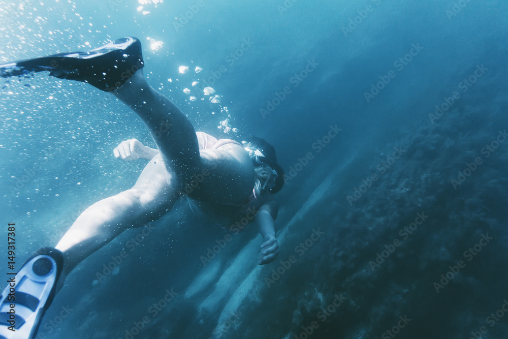 Female freediver swimming in deep sea.