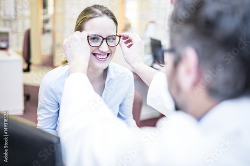 Optometrist trying glasses on woman photo