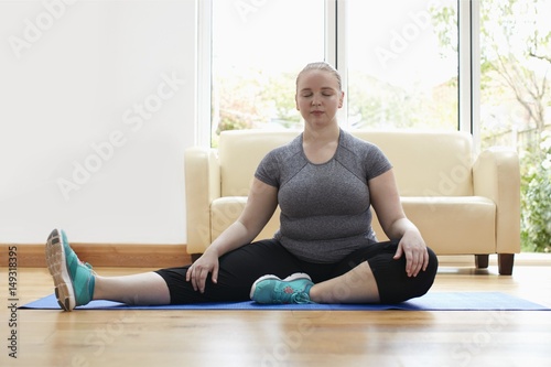 Young woman sitting on floor stretching