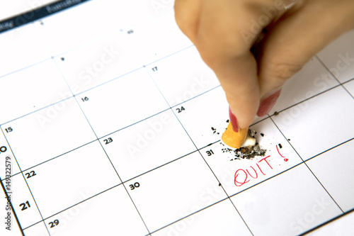 Woman hand destroying cigarette on calendar